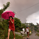Villagers walk in Kota Menara as Mount Soputan erupts in the background.